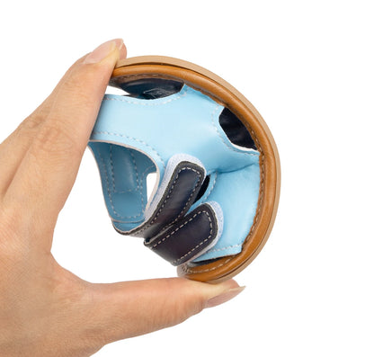 Hand bending a light blue and navy baby sandal to show the flexible anti-slip sole.