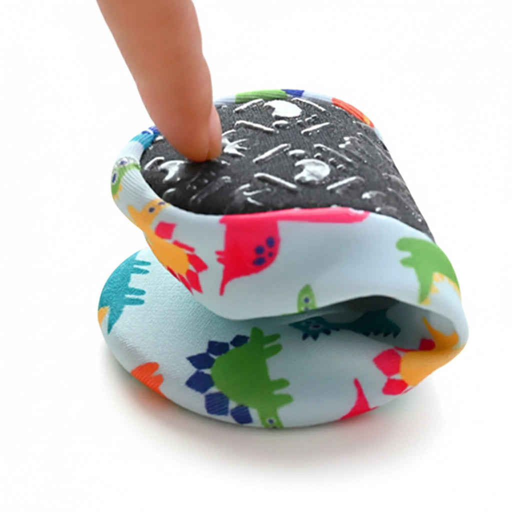 A finger pressing down on a folded Kidsely dinosaur print water shoe to demonstrate the ultra-flexible sole.