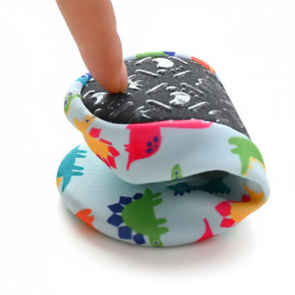 A finger pressing down on a folded Kidsely dinosaur print water shoe to demonstrate the ultra-flexible sole.