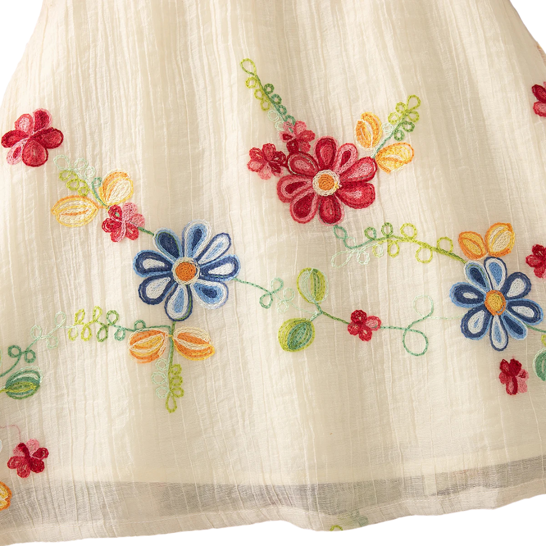 Close-up of the dress hemline featuring large blue and red embroidered flowers with green vine accents.