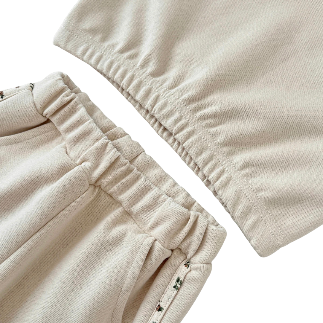 Close-up of the elastic waistband on the cream joggers and the ribbed bottom hem of the matching floral sweatshirt.