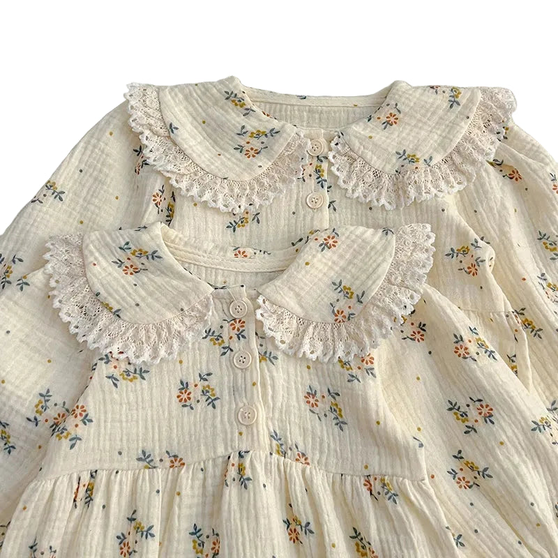 Close-up detail of vintage lace-trimmed Peter Pan collar and botanical print on cream cotton muslin fabric.