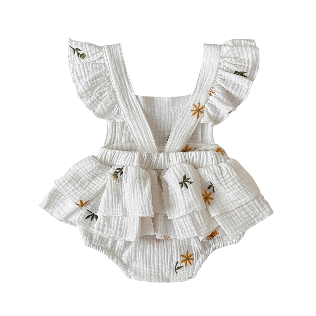 White baby romper with ruffles and floral embroidery on a white background