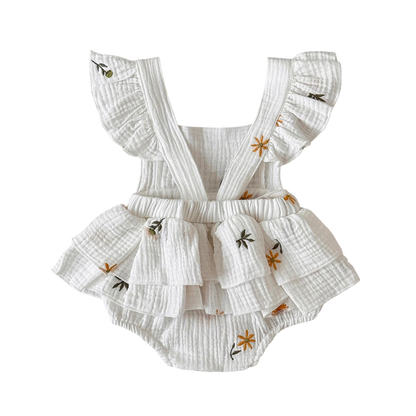 White baby romper with ruffles and floral embroidery on a white background