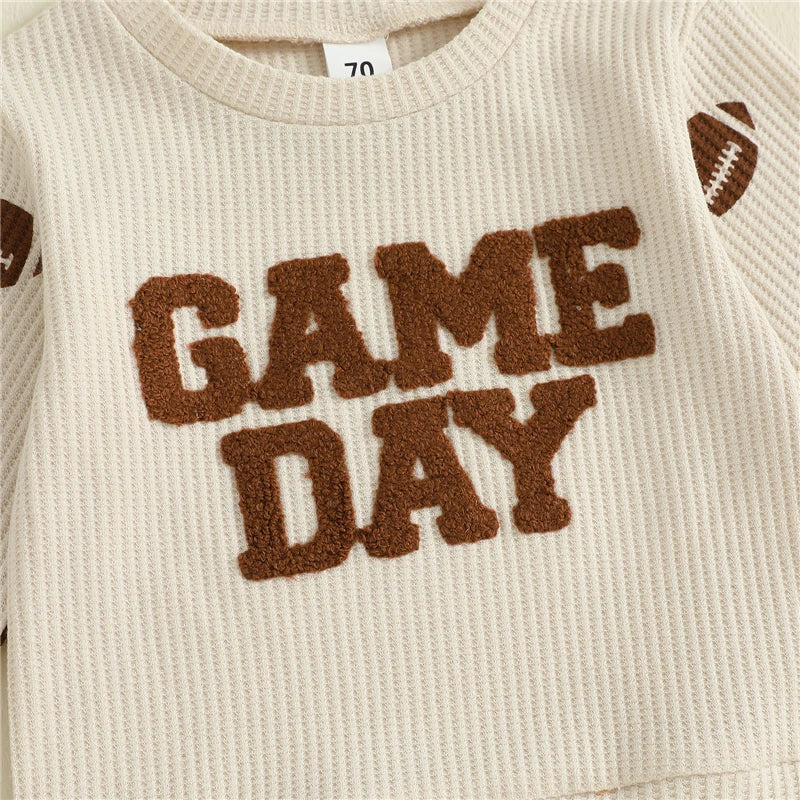 Close-up detail highlighting the fuzzy, textured brown "Game Day" lettering on the toddler's waffle-knit pullover shirt.