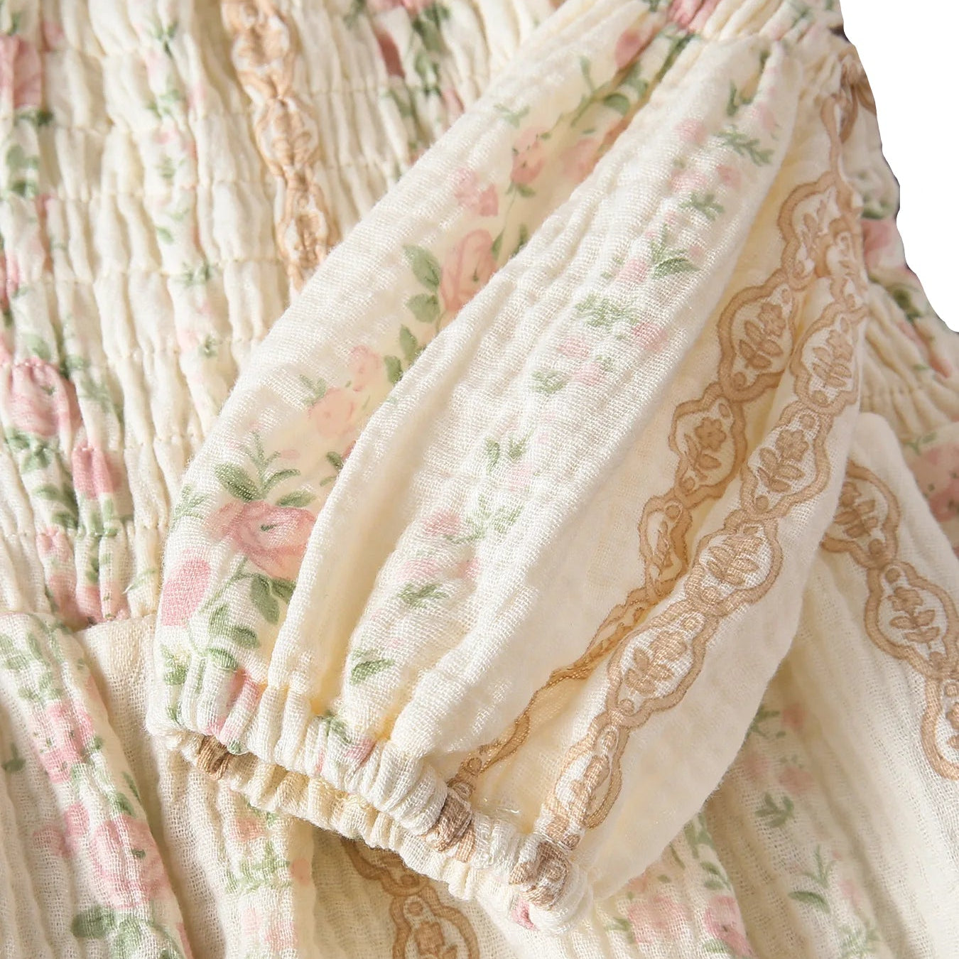 Close-up of the long balloon sleeve on a baby romper, showing the gathered elastic wrist cuff and delicate earthy lace trim.