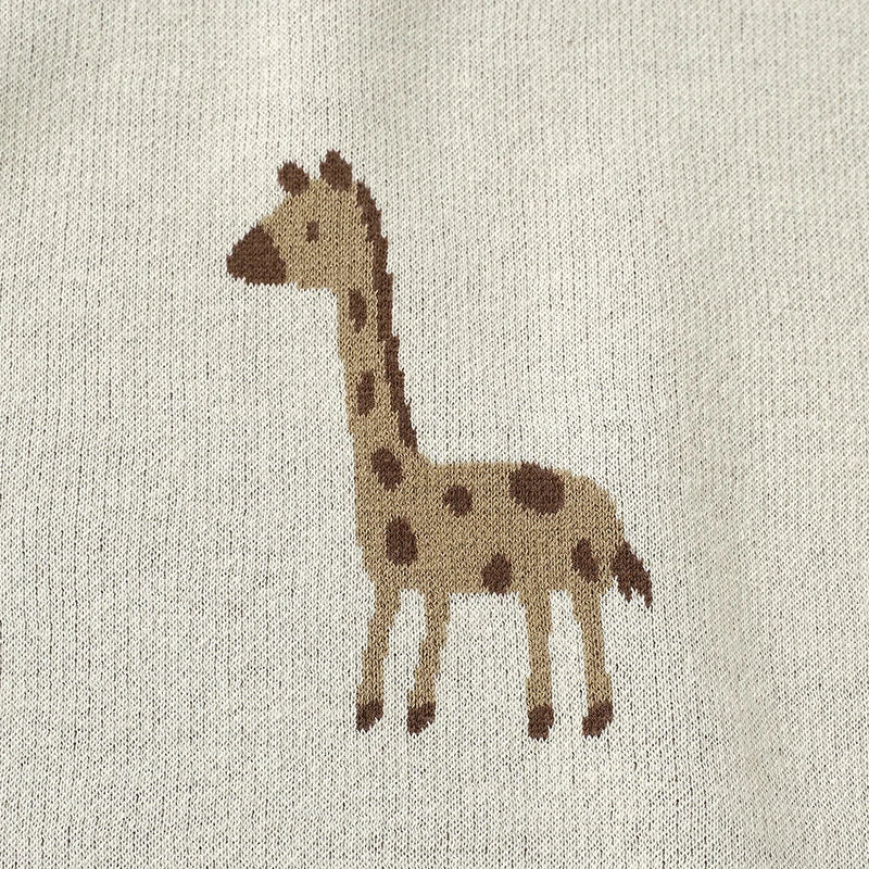 Close-up detail of the woven giraffe pattern on the soft cotton baby blanket