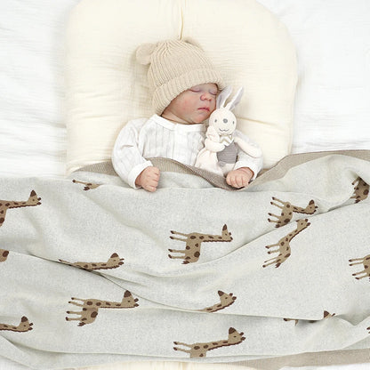 Peaceful infant sleeping comfortably tucked under the cozy giraffe knit baby blanket