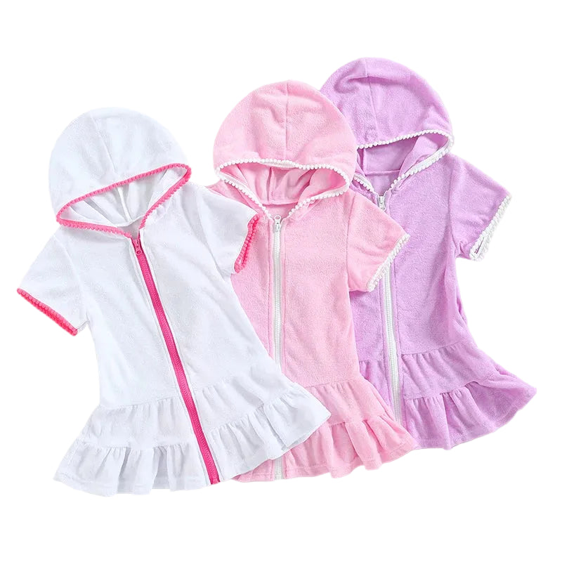 Three girls' hooded terry cloth swim cover-ups in pink, purple, and white featuring zip-up fronts and ruffle hems.