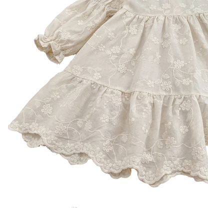 Angled view of girls ivory floral embroidered dress showcasing tiered skirt and long bishop sleeves.