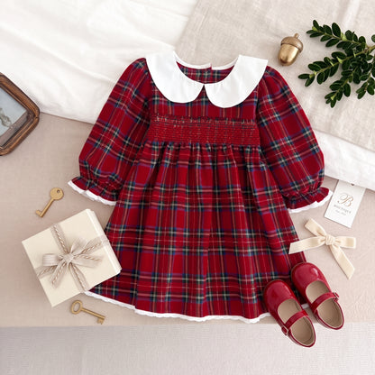 Red plaid smocked holiday dress styled with white Peter Pan collar and Christmas present props