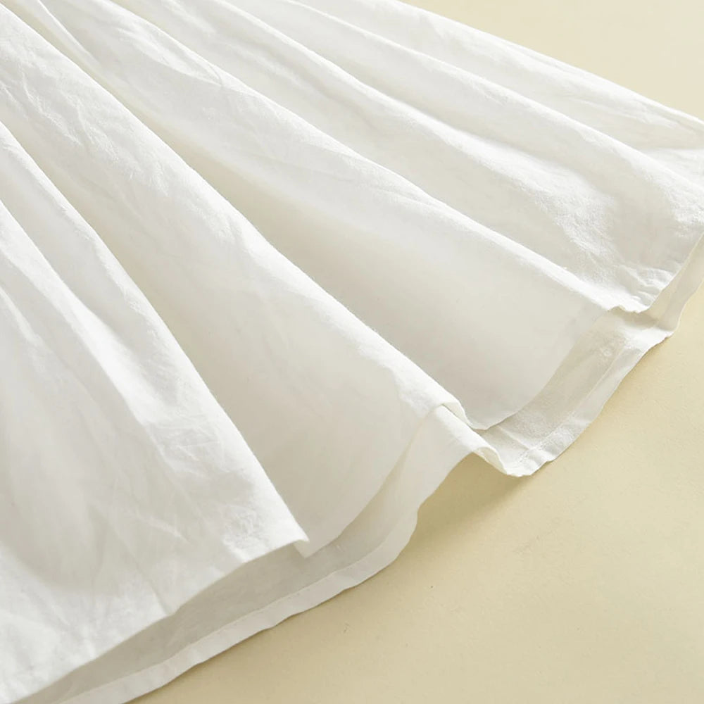 Close-up texture shot of the soft, lightweight white cotton fabric folds of the full A-line dress skirt.