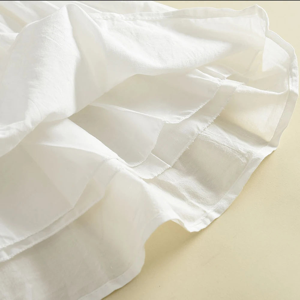 Close-up shot showing the layered tiered ruffles and high-quality hem stitching on the white dress skirt.