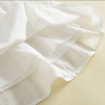 Close-up shot showing the layered tiered ruffles and high-quality hem stitching on the white dress skirt.