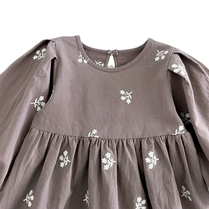 Close-up of the gathered chest and neckline on the gray girls dress, highlighting the white floral embroidery.