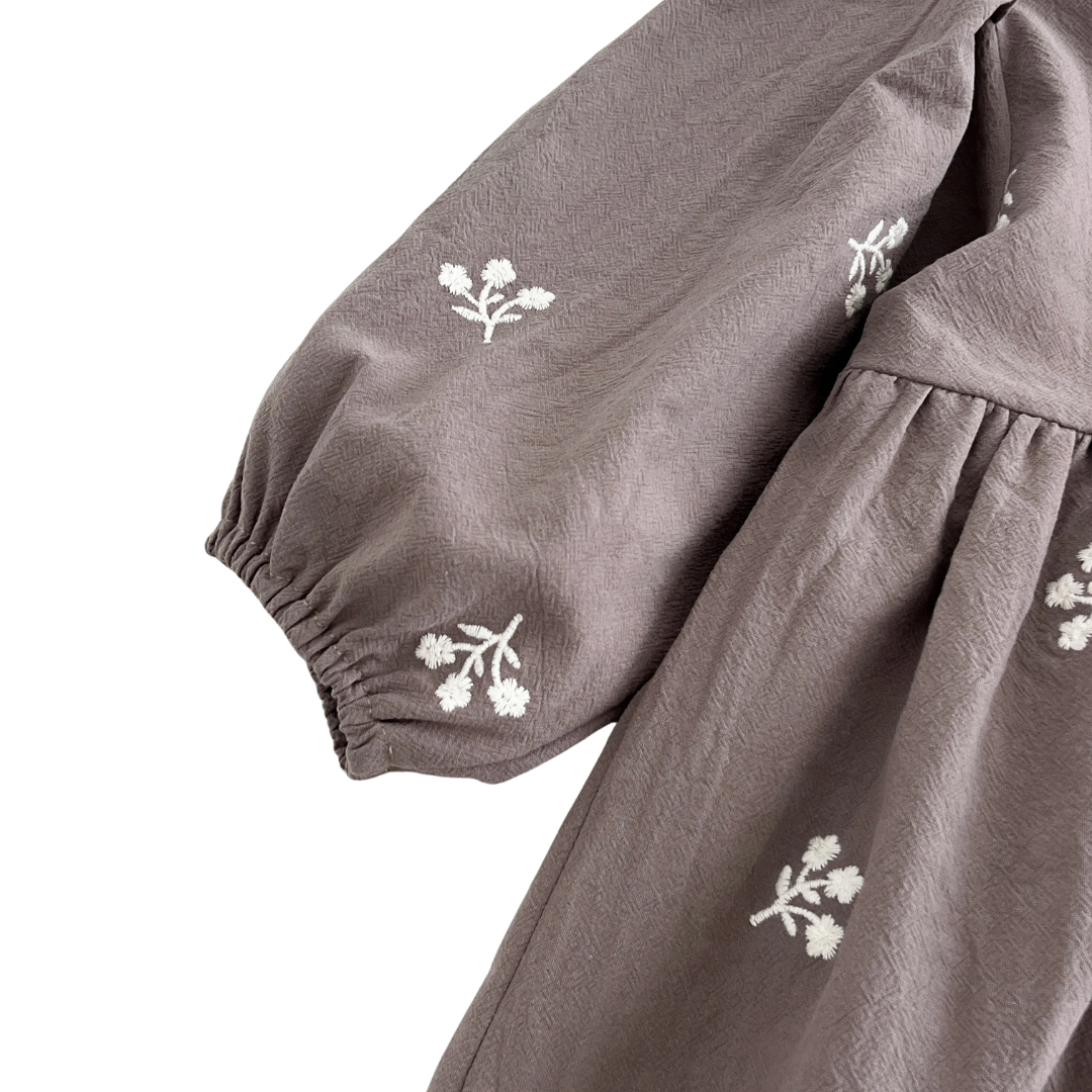 Close-up of the gathered long sleeve on the gray floral embroidered girls dress.