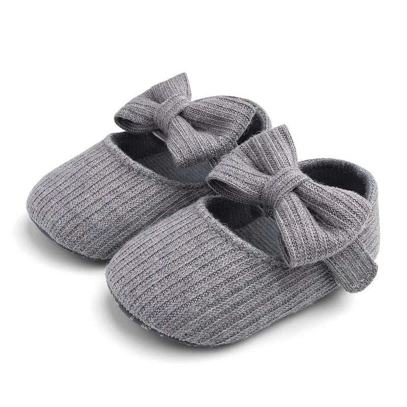 Pair of gray ribbed knit Mary Jane crib shoes with front bows.