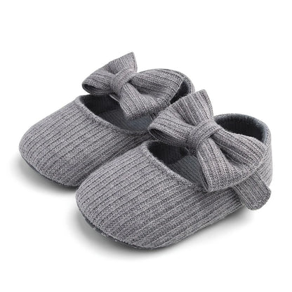 Pair of gray ribbed knit Mary Jane crib shoes with front bows.