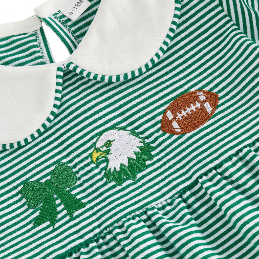 Close-up detail of the chest embroidery on the green striped dress, showing a green bow, bird mascot, and a football.
