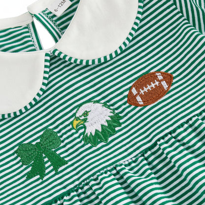 Close-up detail of the chest embroidery on the green striped dress, showing a green bow, bird mascot, and a football.