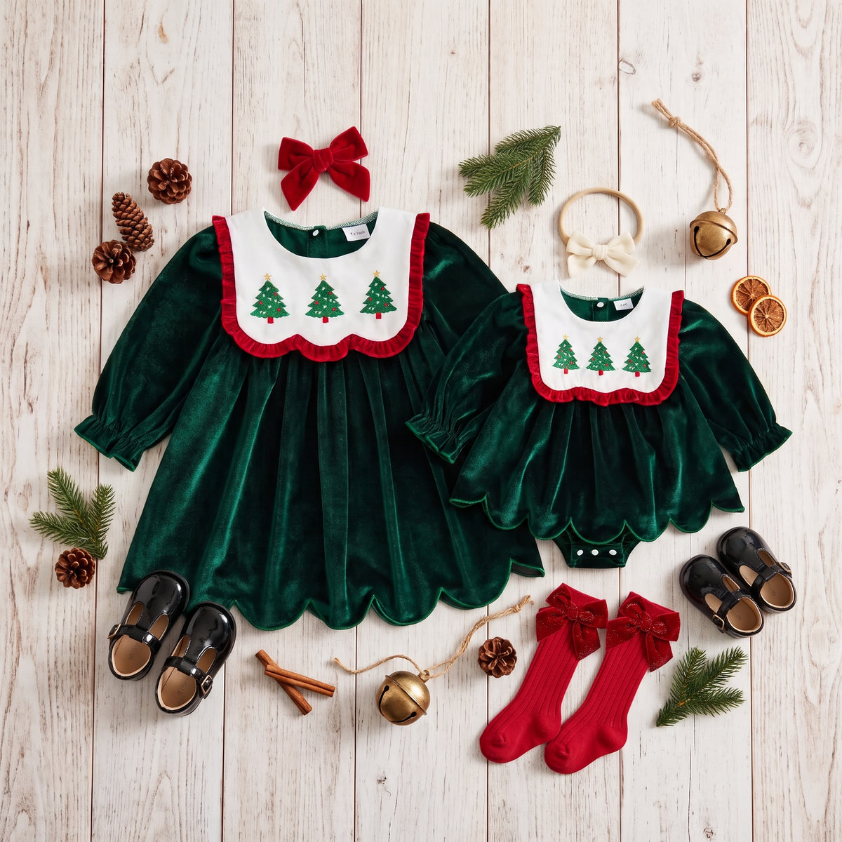 Matching emerald green velvet Christmas dress and baby romper dress flat lay with red socks and Christmas accessories