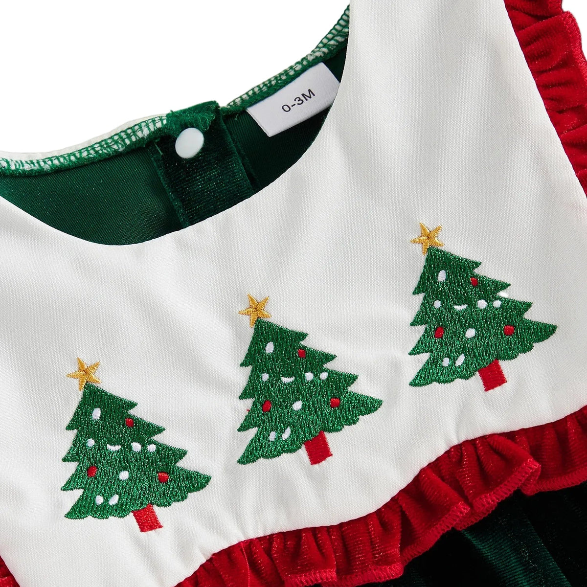 Close-up of white scalloped bib collar with embroidered green Christmas trees and red ruffled edge detail