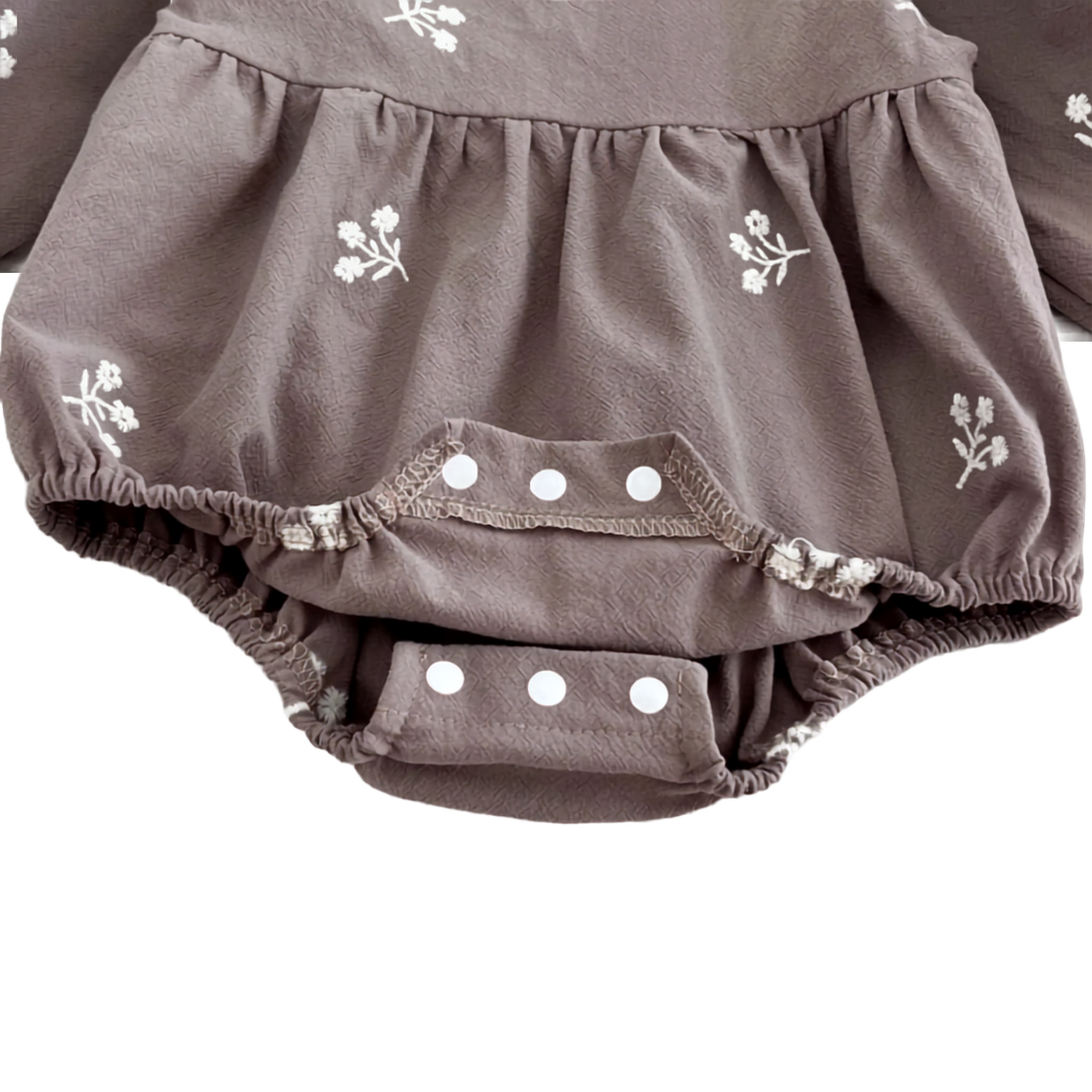 Close-up of the bottom crotch snap closures on the grey baby romper, opened to show the interior.