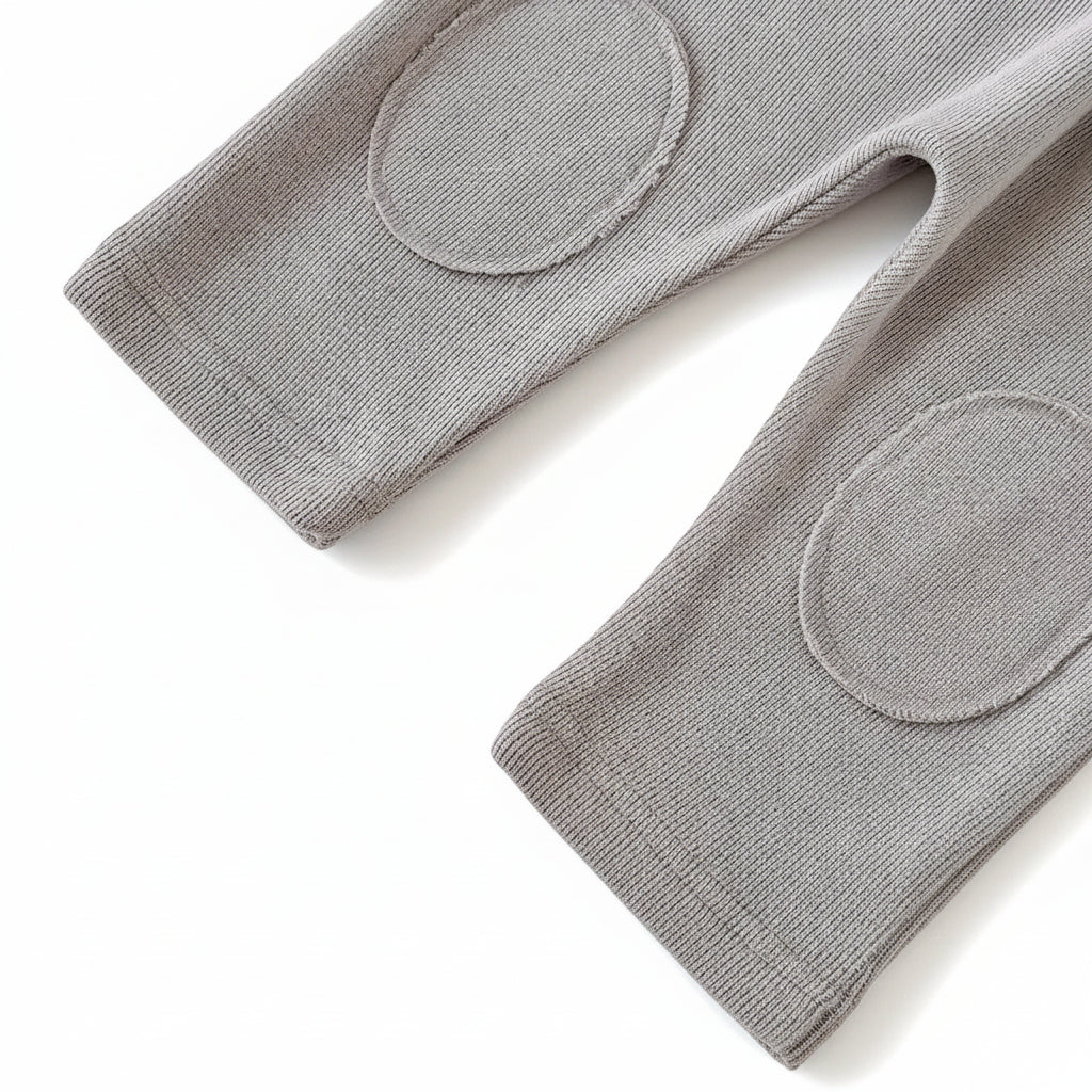 Close-up of the grey knit baby pants highlighting the sewn-on oval knee patches designed for crawling.