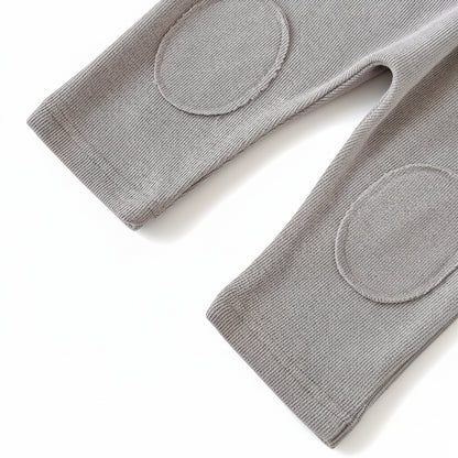 Close-up of the grey knit baby pants highlighting the sewn-on oval knee patches designed for crawling.