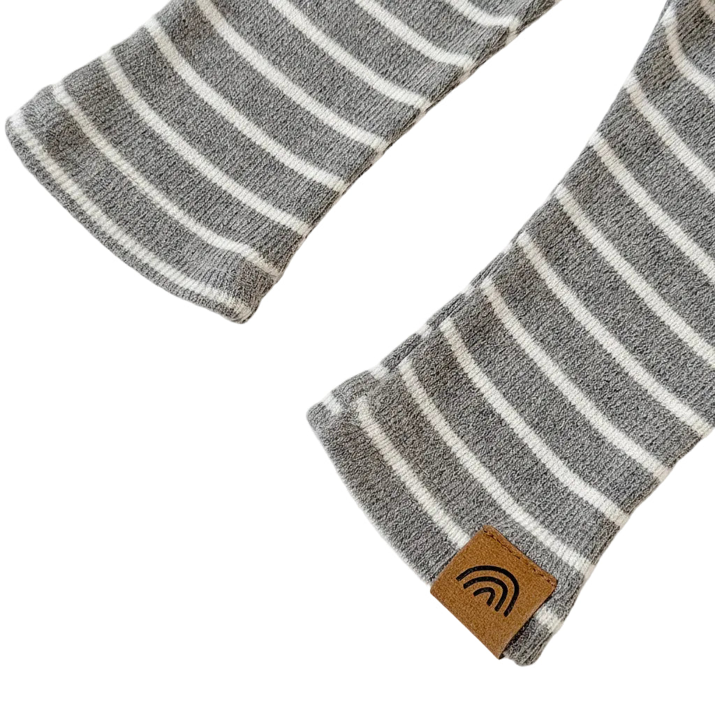 Close-up of the ankle hems on the grey striped toddler pants, showing a small brown rainbow tag on one of the cuffs.