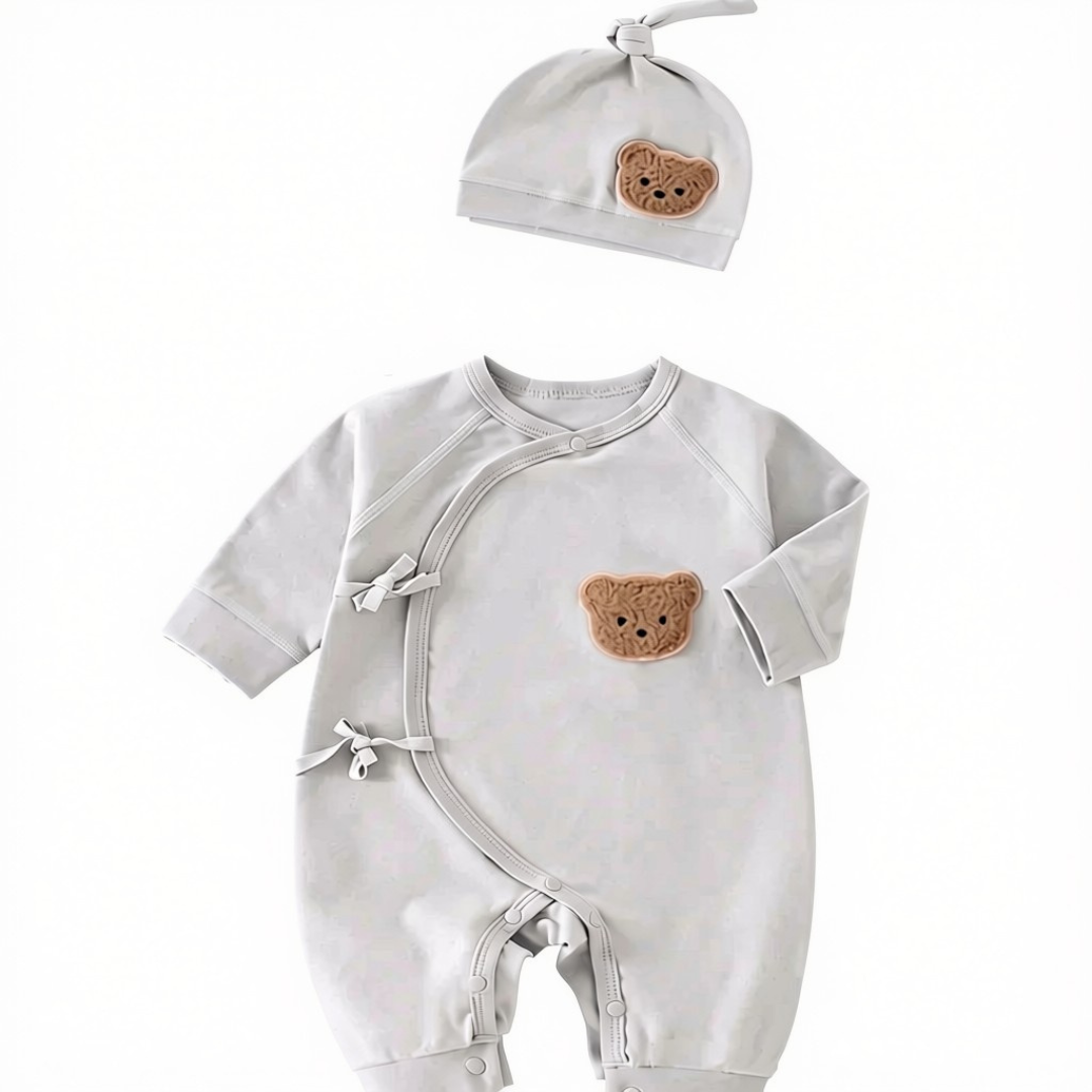 Front view of the grey long-sleeve baby sleepsuit with side snaps and matching teddy bear patch hat.