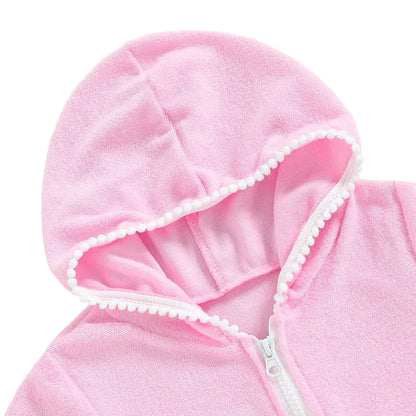 Detailed view of the hood and white zipper on a pink girls' terry cloth beach dress with decorative pom-pom edging.