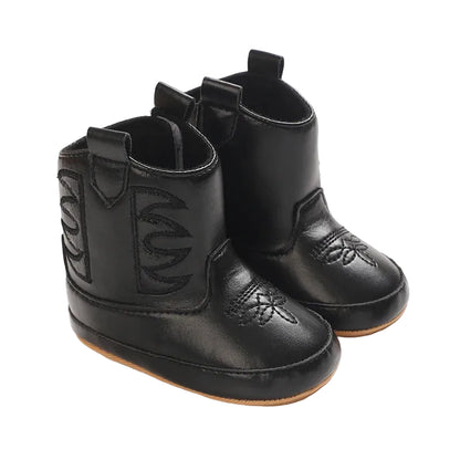 A pair of black infant western boots displayed at an angle, highlighting the classic side cutout design and durable PU leather construction.