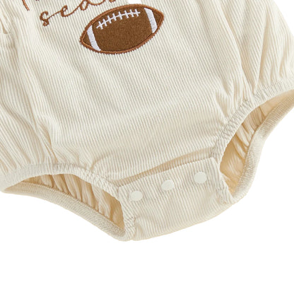 Detailed view of the elasticized leg openings and the secure three-button bottom diaper snap closures on the cream corduroy bubble romper.