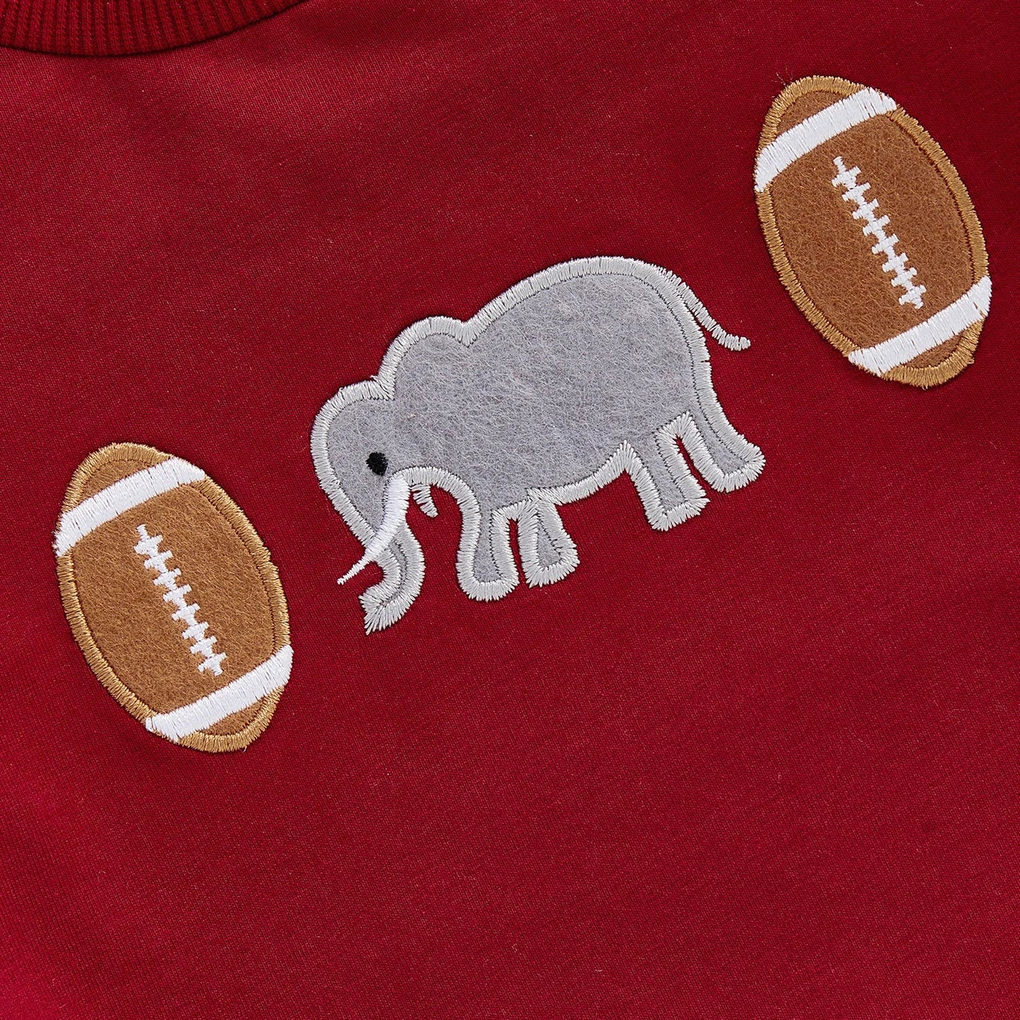Close-up of high-quality vintage chain-stitch embroidery featuring a grey elephant and classic footballs on a crimson infant romper.