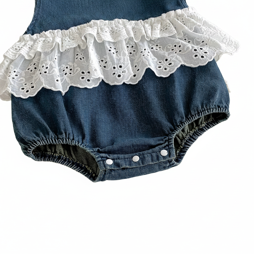 Detailed view of the reinforced white bottom snaps and elastic leg openings on an infant denim bubble romper.