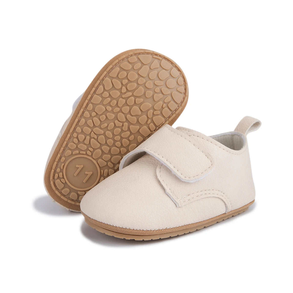 Bottom view of beige infant first walker shoes displaying the textured anti-slip rubber sole.