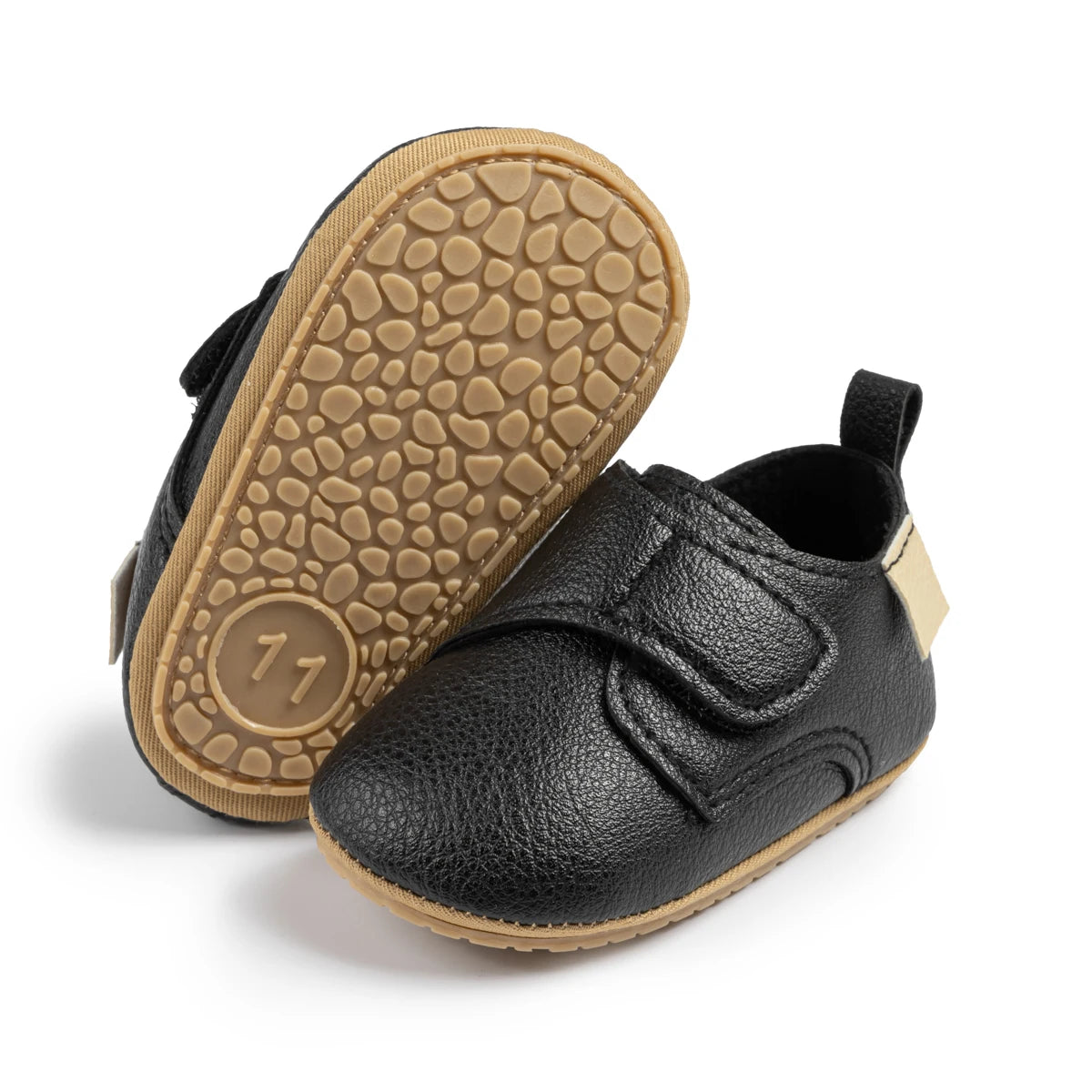 Bottom view of black infant first walker shoes highlighting the textured anti-slip rubber sole.
