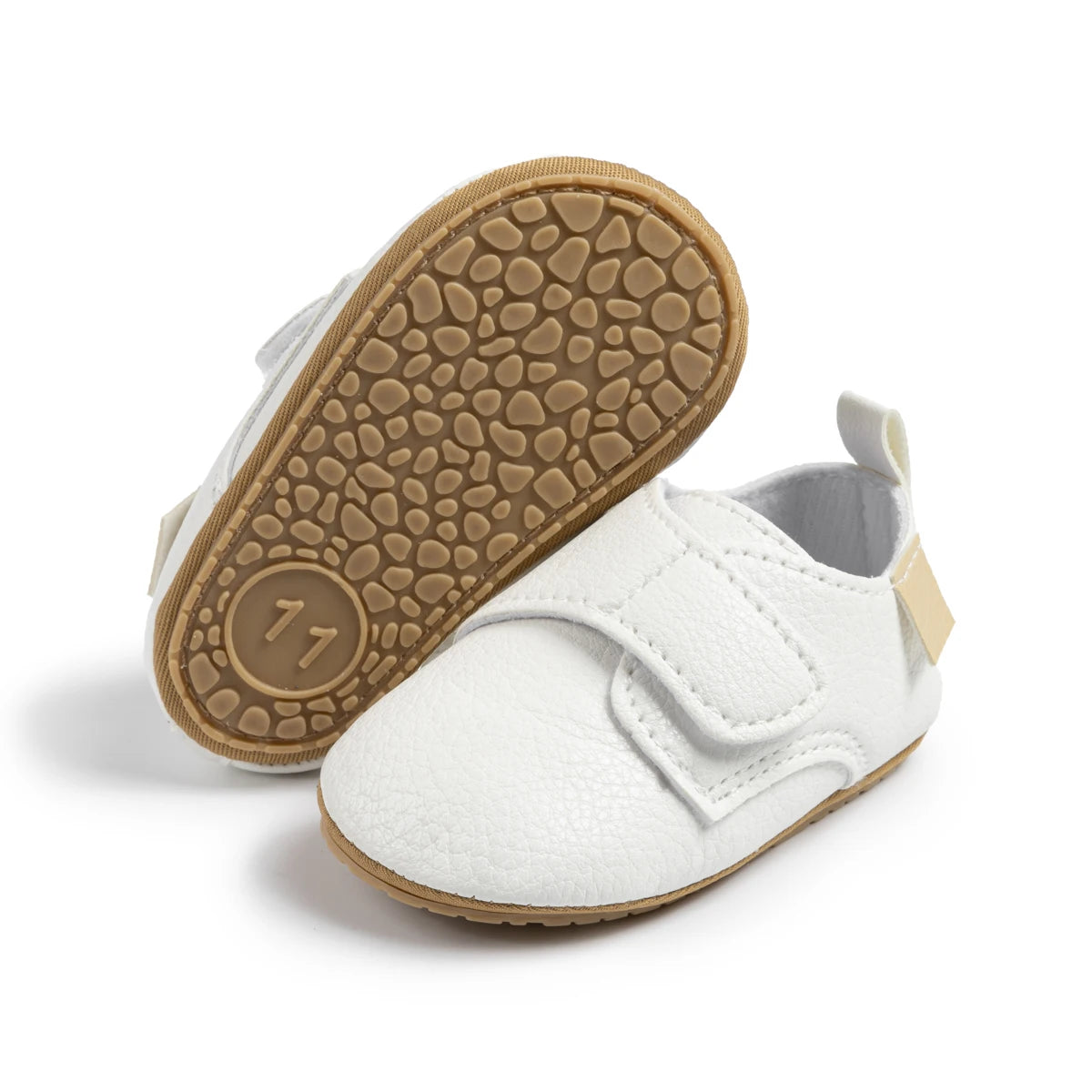 Bottom view of white infant first walker shoes showing the textured anti-slip rubber sole.