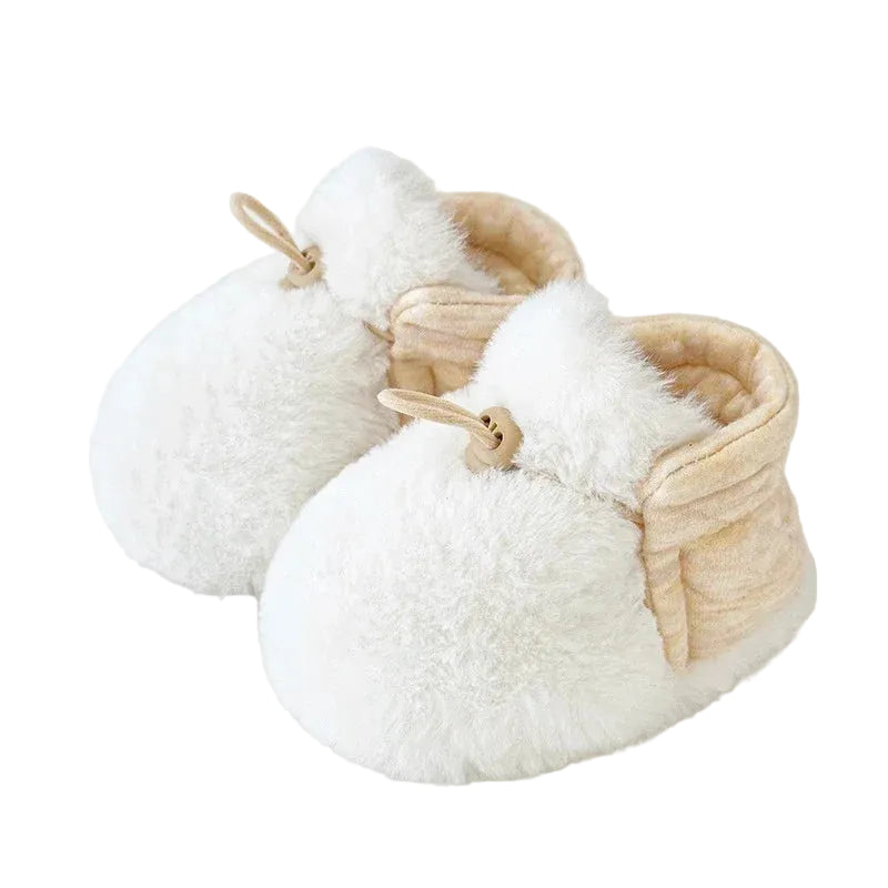 A pair of white infant soft fleece booties with an adjustable elastic strap.