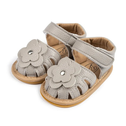 Grey newborn girl dress sandals with floral detail and flexible first-walker soles.
