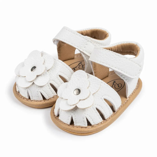 White infant baby girl flower sandals with soft non-slip soles and adjustable ankle strap.