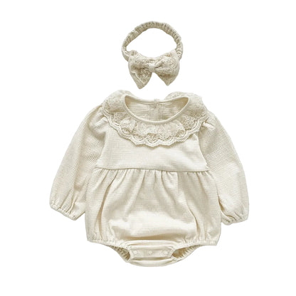 Studio product shot of the cream off-white long sleeve baby girl bubble romper with a lace trim collar.