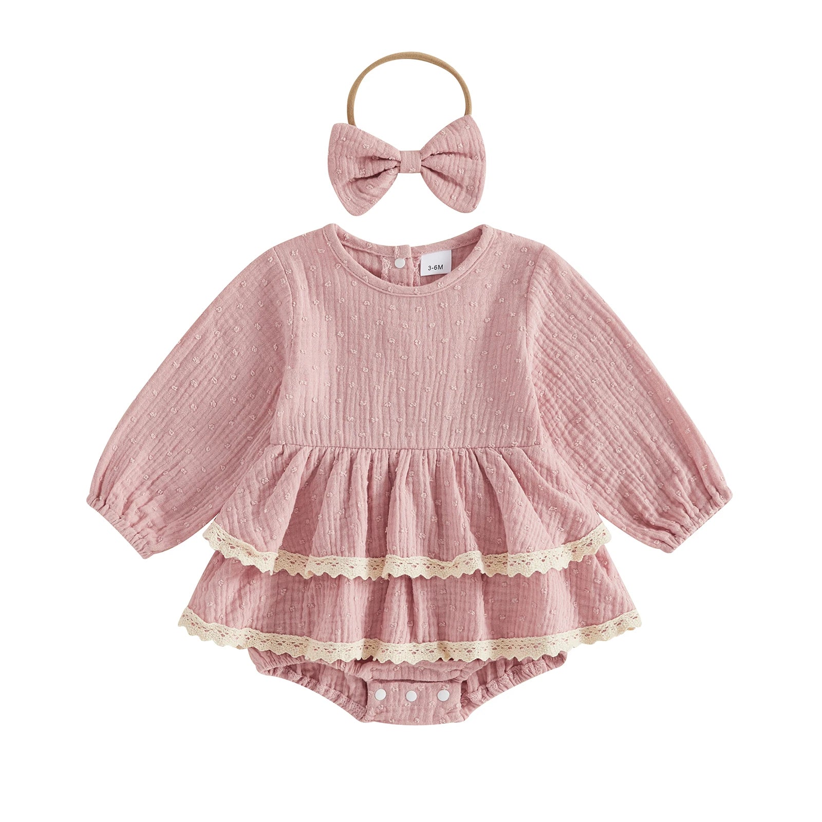 Flat lay of a vintage-inspired dusty pink infant girl puff sleeve romper dress with lace trim and matching bow headband.