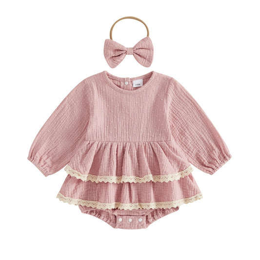 Flat lay of a vintage-inspired dusty pink infant girl puff sleeve romper dress with lace trim and matching bow headband.