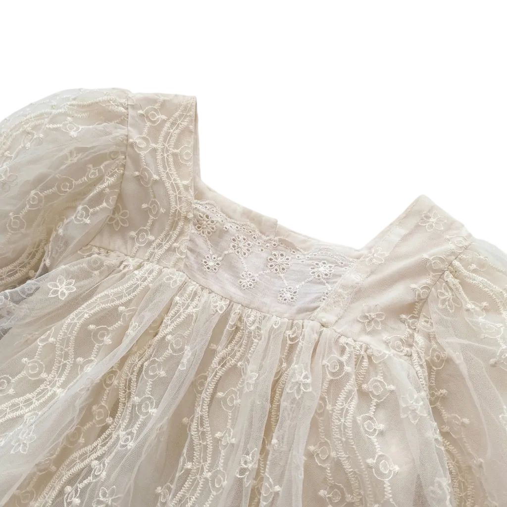 Close-up of the square neckline and intricate bodice embroidery on an infant girl ivory lace romper.