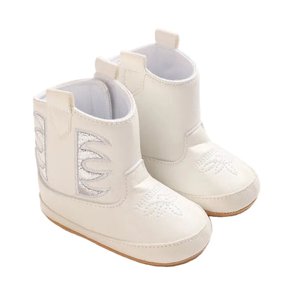 A pair of white infant baby girl cowboy boots featuring silver metallic side panels and rubber soles on a white background.