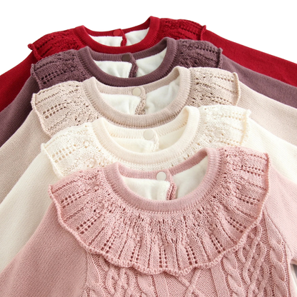 Close-up view of stacked ruffle frill collars on baby cable knit sweater bodysuits in various autumn colors.