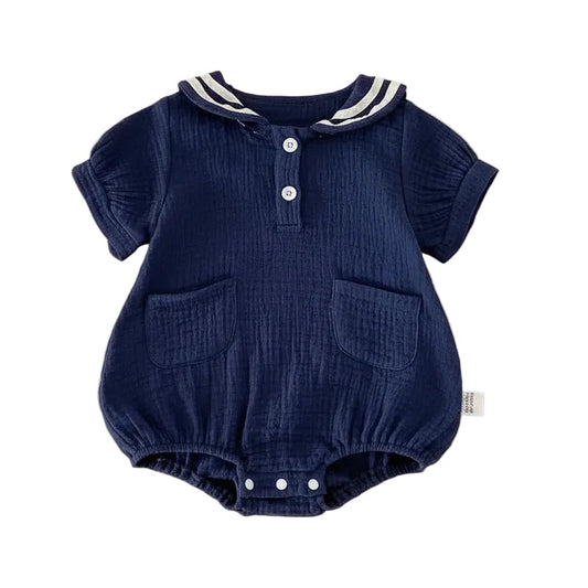 Flat lay of a Deep Sea navy blue muslin baby bubble romper with white nautical stripes on the sailor collar and a relaxed unisex fit.