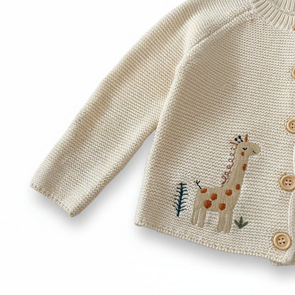 Close-up of the long raglan sleeve and stitched giraffe embroidery details on the cream cotton baby cardigan.